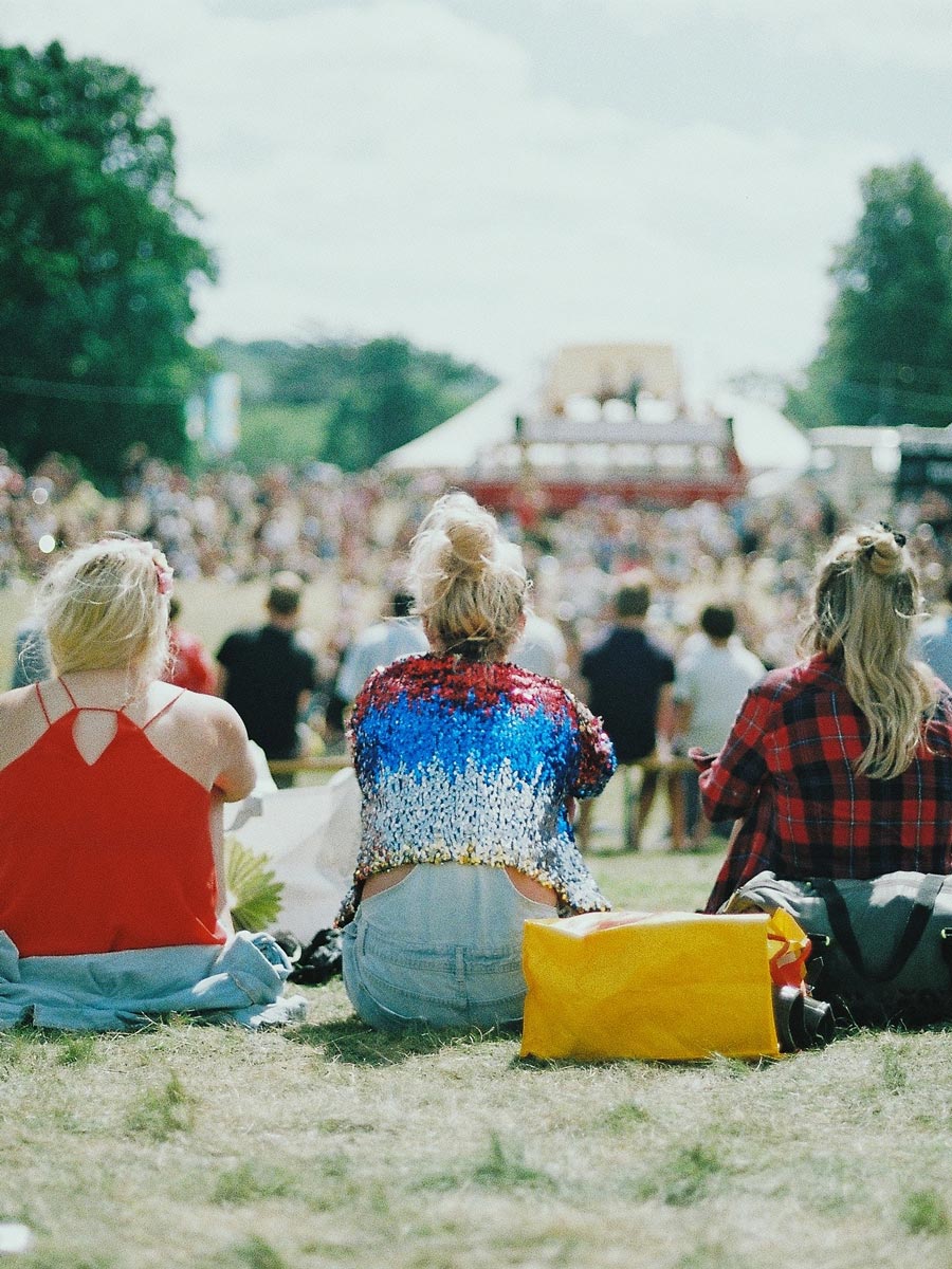 Girls Sitting On The Grass At A Festival